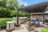 Charming outdoor space featuring a modern pergola with string lights, multiple stainless steel grills, and vibrant blue picnic tables, perfect for entertaining.