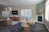 Stylish and modern living area with elegant chandelier, cozy armchairs, and a chic dining setup. Bright windows enhance the sophisticated decor, featuring a distinctive fireplace and tasteful decorative accents.