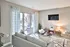 Contemporary living room with cozy gray sofa, stylish decor, wall-mounted TV, and sliding doors leading to a balcony.