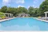 Inviting outdoor pool area surrounded by lush greenery, featuring comfortable loungers and a charming pool house.