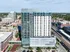 Stunning aerial view of a modern high-rise apartment building in a vibrant urban setting, showcasing the sleek design and proximity to city amenities.