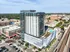 Modern high-rise apartment building with glass facade, featuring rooftop pool and green spaces, nestled in vibrant urban area.