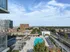 Breathtaking rooftop view with a sleek swimming pool, lounge chairs, and panoramic cityscape under a clear blue sky.
