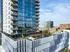 Modern high-rise apartment building with sleek balconies, reflecting blue sky and vibrant cityscape.