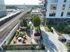 Modern apartment complex with a lush rooftop garden, stylish outdoor seating area, and scenic views of the city skyline and railway tracks.