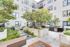 Modern apartment courtyard featuring lush greenery, built-in grills, and stylish seating, ideal for outdoor relaxation.