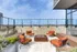 Modern rooftop terrace with stylish orange cushioned seating and a central fire pit, offering a perfect spot for relaxation with panoramic views.