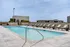 Luxurious rooftop pool area with sleek lounge chairs and a stunning city view, perfect for relaxation and leisure.