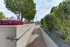 Inviting rooftop garden walkway with lush greenery, vibrant foliage, and city skyline views.