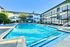Inviting apartment complex with a sparkling outdoor swimming pool, surrounded by lush greenery and modern sun loungers for ultimate relaxation.