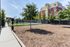Charming outdoor community area with lush green playground, shady trees, and modern apartment building in the background.