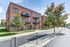Charming brick apartment building with private balconies, surrounded by lush greenery and modern amenities on a sunny day.