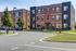Charming modern apartment building with a red brick exterior, stylish black accents, and beautifully manicured landscaping.