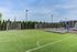 Inviting residential sports complex with a vibrant green soccer field and modern adjacent playground under a clear blue sky.