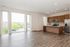 Bright open-concept apartment with floor-to-ceiling windows, modern kitchen, and sleek hardwood floors.