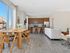 Bright open-concept apartment with modern kitchen, elegant dining area, and cozy living space featuring sleek hardwood floors and large windows.