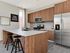 Modern kitchen with sleek wood cabinetry, stainless steel appliances, and a stylish breakfast bar with chic seating in a bright, welcoming space.