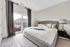 Bright and inviting bedroom with elegant decor, plush pillows, and natural light streaming through large windows.