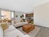 Bright and inviting living room with modern decor, large windows, and an open-plan kitchen, perfect for entertaining.