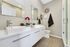 Chic bathroom featuring a modern double vanity with stylish mirrors, elegant orchid decor, cozy towels, and a walk-in shower.