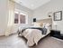Bright and cozy bedroom with elegant decor, featuring a plush bed, modern lamps, and stylish artwork, perfect for relaxation and comfort.