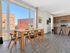 Bright and modern apartment with a spacious open-concept kitchen and dining area, highlighted by large windows and sleek wooden flooring, offering a stylish urban view.