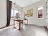 Elegant home office with a modern wooden desk, stylish chair, and large windows offering natural light and urban views.