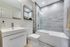 Modern bathroom with sleek white sink, elegant gray tile bathtub, and stylish mirrored cabinet, ideal for luxury living.