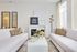 Elegant living room with modern decor, featuring plush white sofas, stylish geometric accents, and a cozy fireplace.