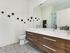 Contemporary bathroom with dual sinks, sleek wooden cabinetry, and stylish black wall accents.