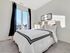 Inviting bedroom with large windows, soft carpeting, and elegant decor featuring a plush bed and soothing natural light.