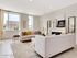 Bright, contemporary living room featuring elegant sofas, modern artwork, and large windows that allow natural light to fill the space.