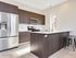 Modern kitchen with sleek dark wood cabinets, stainless steel appliances, and a stylish island with bar stools.