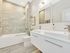 Elegant bathroom boasting dual sinks, luxurious tile accents, and a spacious glass-enclosed shower.