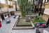 Modern apartment courtyard featuring stylish seating, a tranquil fountain, lush greenery, and contemporary design elements.