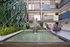 Chic apartment atrium featuring a serene water fountain, lush greenery, and modern seating areas, creating an inviting oasis atmosphere.