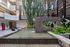 Modern apartment complex courtyard showcasing a serene water feature, lush greenery, and towering cactus plants for a tranquil outdoor ambiance.