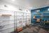 Modern mailroom with sleek metal shelving units for organized package storage labeled by floor numbers, bright lighting, and a striking blue accent wall.