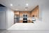 Modern kitchen with sleek white countertops, wooden cabinetry, stainless steel appliances, and elegant lighting.