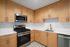 Modern kitchen with sleek stainless steel appliances, warm wooden cabinetry, and elegant white countertops.