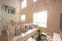Bright and inviting living room with elegant modern decor, featuring a plush white sofa, chic coffee table with tulip arrangement, and dining area with stylish yellow-accented chairs.