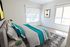 Bright, airy bedroom with a modern design featuring large windows, vibrant teal accents, and elegant decor.