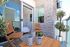 Inviting balcony with chic wooden furniture, lush potted plants, and elegant stone wall; perfect for relaxation and enjoying the view.