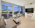 Modern living room with elegant decor, featuring a cozy sofa, sleek TV, and large windows offering a stunning city view.