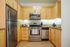 Modern kitchen featuring stainless steel appliances, warm wooden cabinetry, and granite countertops.