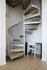 Elegant spiral staircase with sleek metal railings beside a minimalist white desk and chair setup, enhancing the modern aesthetic.