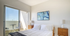 Bright and inviting bedroom with a comfortable bed, stylish artwork, and access to a cozy private balcony.