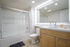 Bright and modern bathroom featuring a sleek glass-enclosed shower, elegant vanity with ample storage, and stylish lighting.