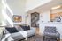 Bright and modern open-concept living area with spiral staircase, cozy seating, and a sleek kitchen.