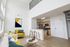 Modern apartment interior with a bright living area, sleek kitchen, and contemporary decor featuring vibrant yellow accents.